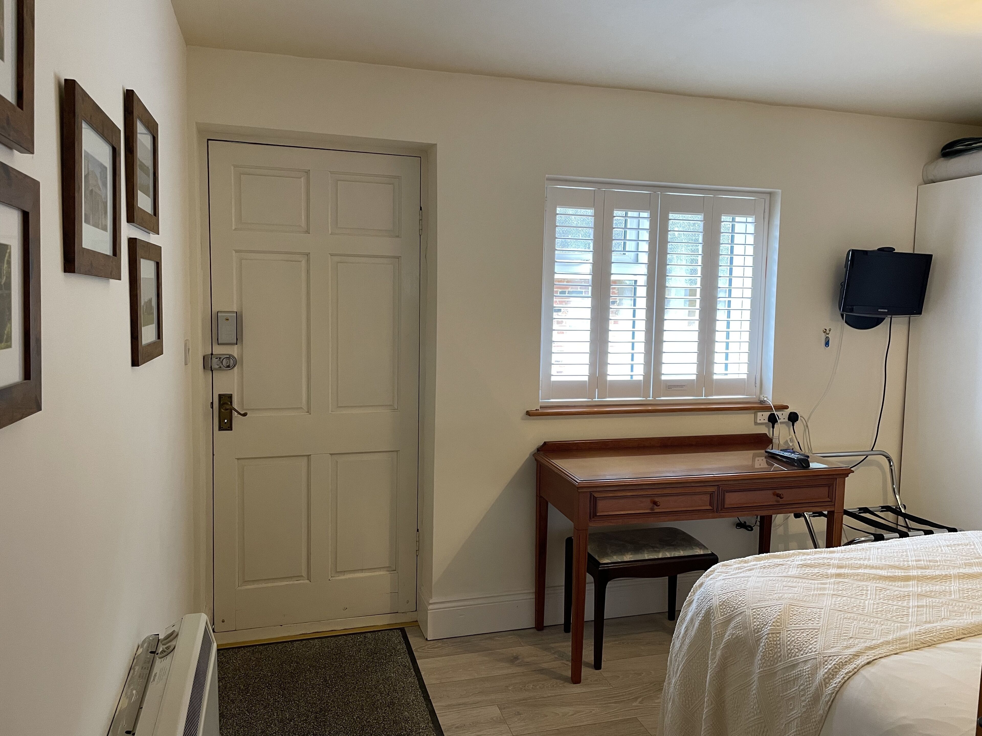 Une chambre à coucher avec un lit, un bureau, une fenêtre et un téléviseur.