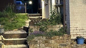 A stone staircase leading to a house with a brick exterior and a wooden deck.