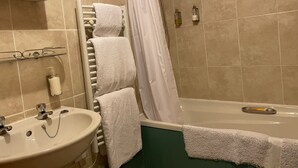 A bathroom with a bathtub, a sink, and a towel rack with multiple towels.
