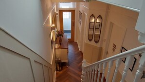 A staircase with red carpeted steps leading to a landing with a door and a hallway. - The Clifton at Paignton (Paignton)