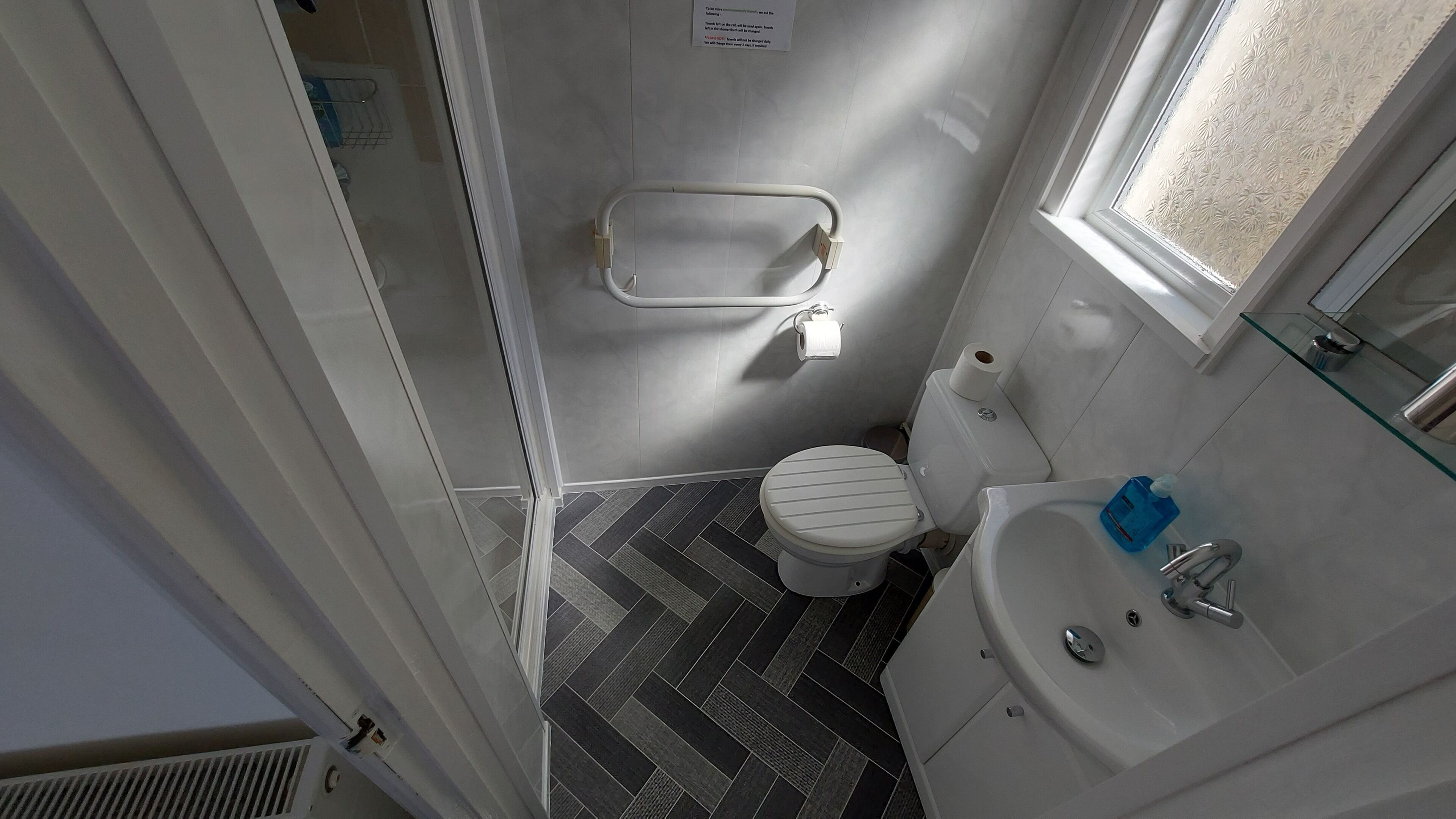 A compact bathroom with a toilet, a glass shower enclosure, and a sink with a mirror.