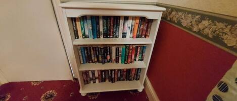A corner bookshelf with multiple shelves of books.