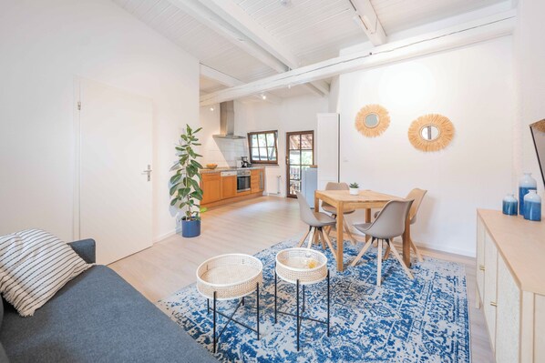 Relax in a cozy seating area with a sofa and dining table near a well-equipped kitchen.