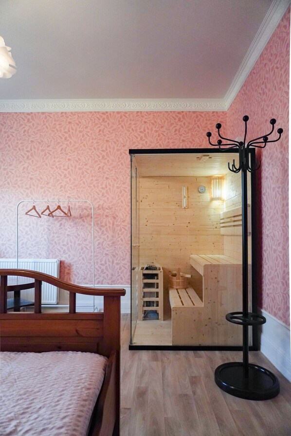 A bedroom with a wooden bed, a mirror, and a wooden sauna visible through an open door. - Seebad Ahlbeck - spacious apartment with sea view close to the beach (Heringsdorf)