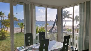 A conservatory with a table and chairs, overlooking a beach and the sea. - Beachfront the dream holiday (saint martin)
