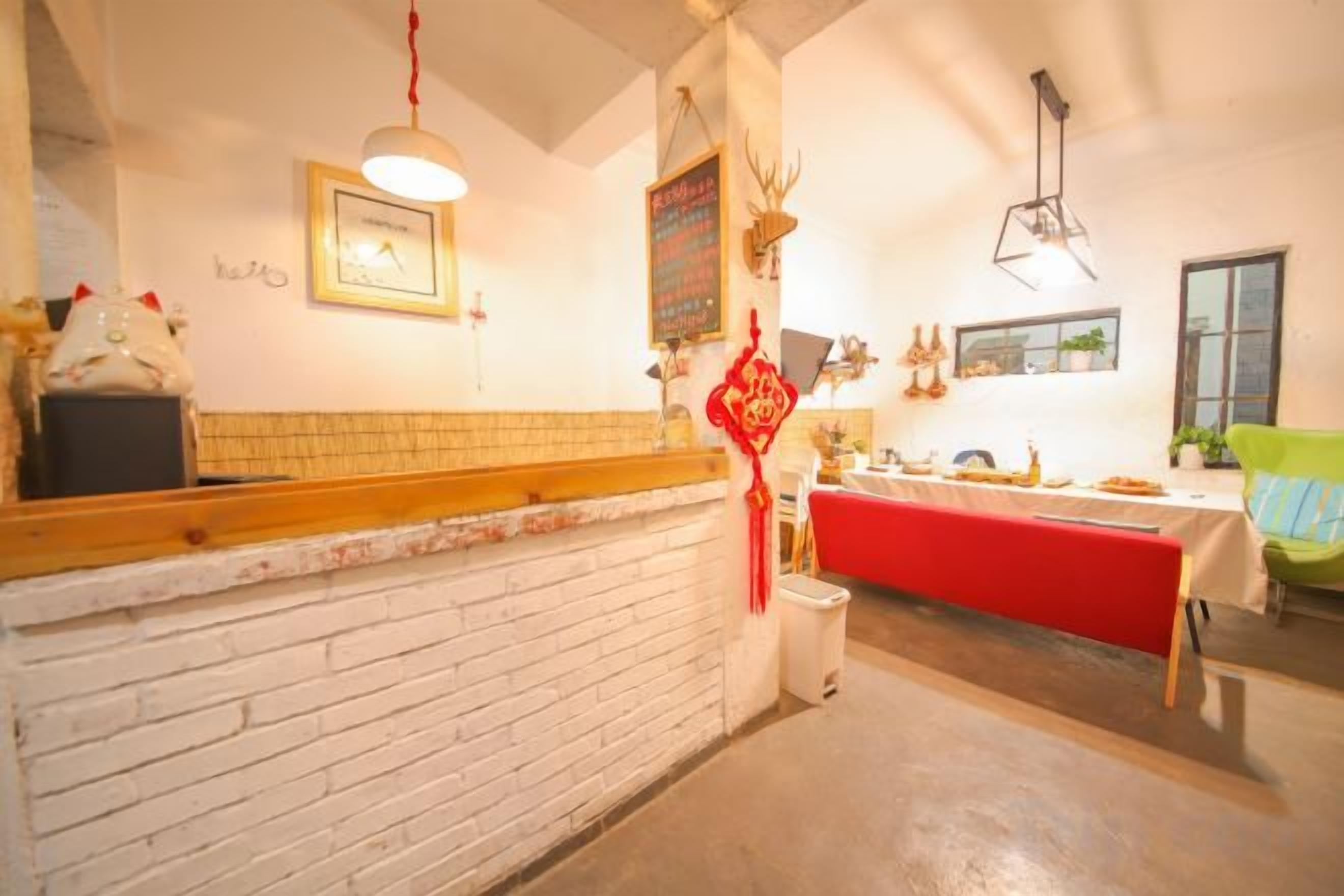 A restaurant with a brick wall, a red table, and a hanging light fixture.