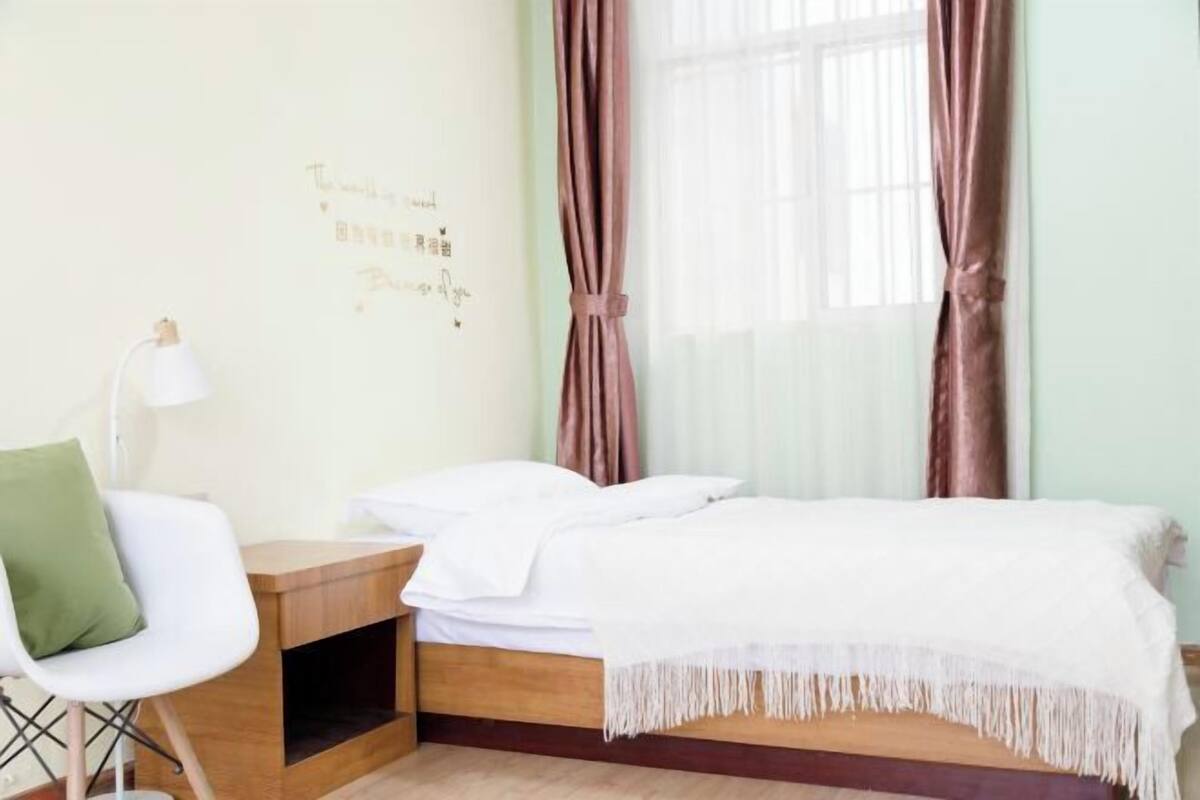 A bedroom with a bed, bedside table, chair, and a wall with text.