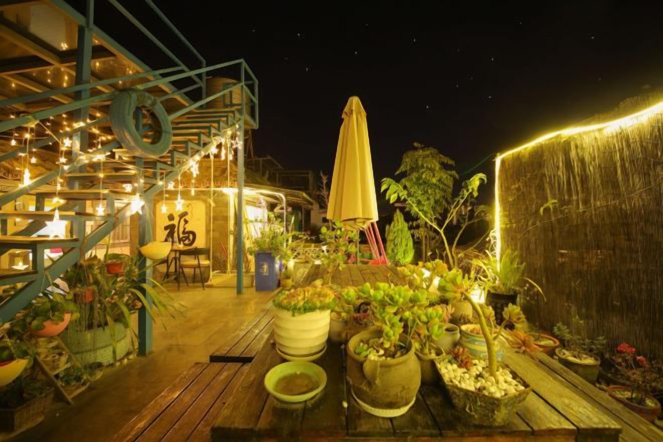 Un espace extérieur aménagé en terrasse, avec des plantes en pot, une plateforme en bois et un escalier menant à un niveau supérieur.