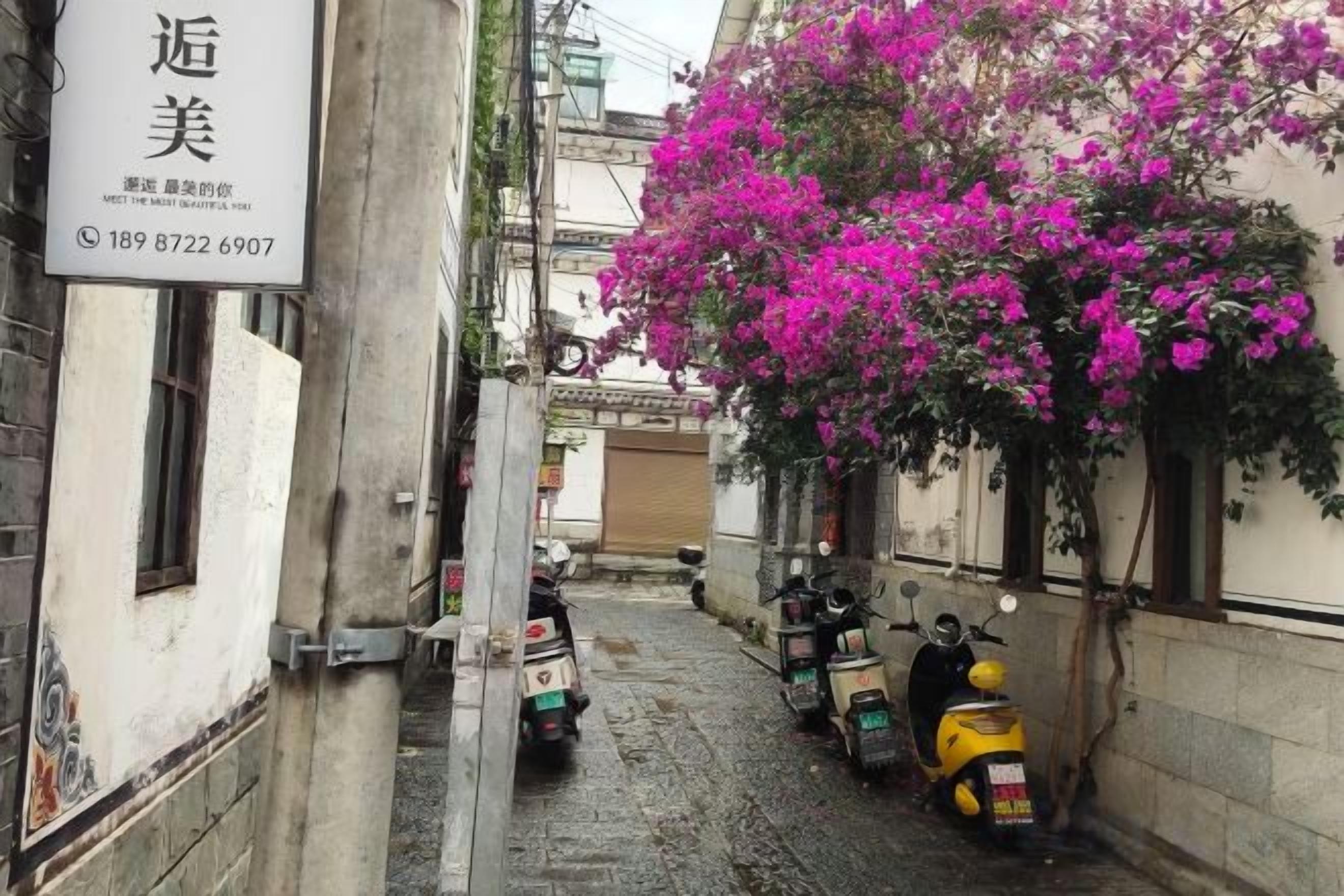A narrow street with parked scooters and a building with a sign.