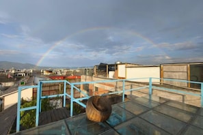 A glass-walled room with a view of a cityscape and a rainbow.