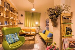 Una sala de estar acogedora con un sillón verde, un sofá, una mesita de centro y una estantería.
