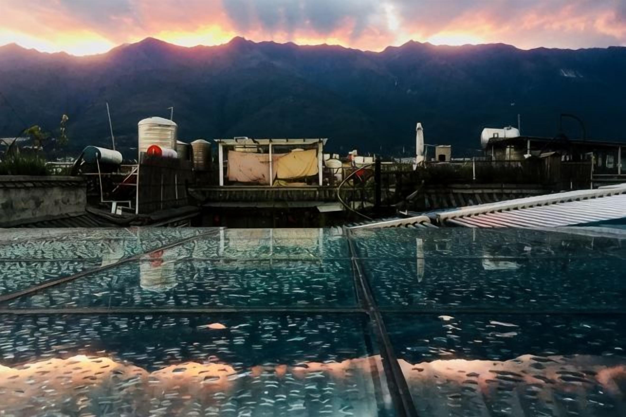 Une piscine sur le toit offrant une vue sur les montagnes, entourée de bâtiments industriels.