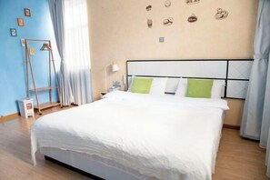 A neatly made bed with white bedding and green pillows, a bedside lamp, and a wall with decorative stickers. - Meet Inn (Dali City)