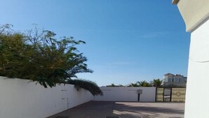 A courtyard with a tiled floor, a white wall, and a tree. - Al Dhait Residence (Ras Al Khaimah)