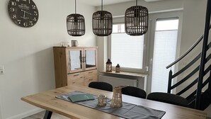 Ein Essbereich mit einem Holztisch, Bänken und einer Wanduhr.
