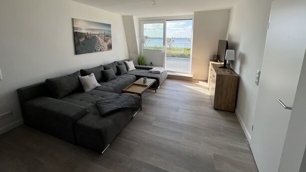 Ein modernes Wohnzimmer mit einem Ecksofa, einem Couchtisch und einer TV-Konsole.