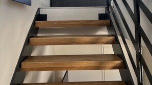 Eine moderne Treppe mit Holzhäuschen und schwarzen Metallgeländern.