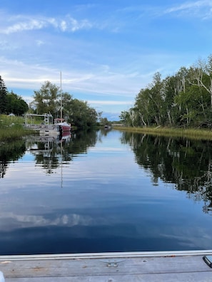 A calm river with boats docked on the left, surrounded by trees and greenery. - Tranquility on the River (Britt)