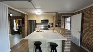 Una cucina moderna con isola centrale, elettrodomestici in acciaio inossidabile e una parete decorata con mattoni.
