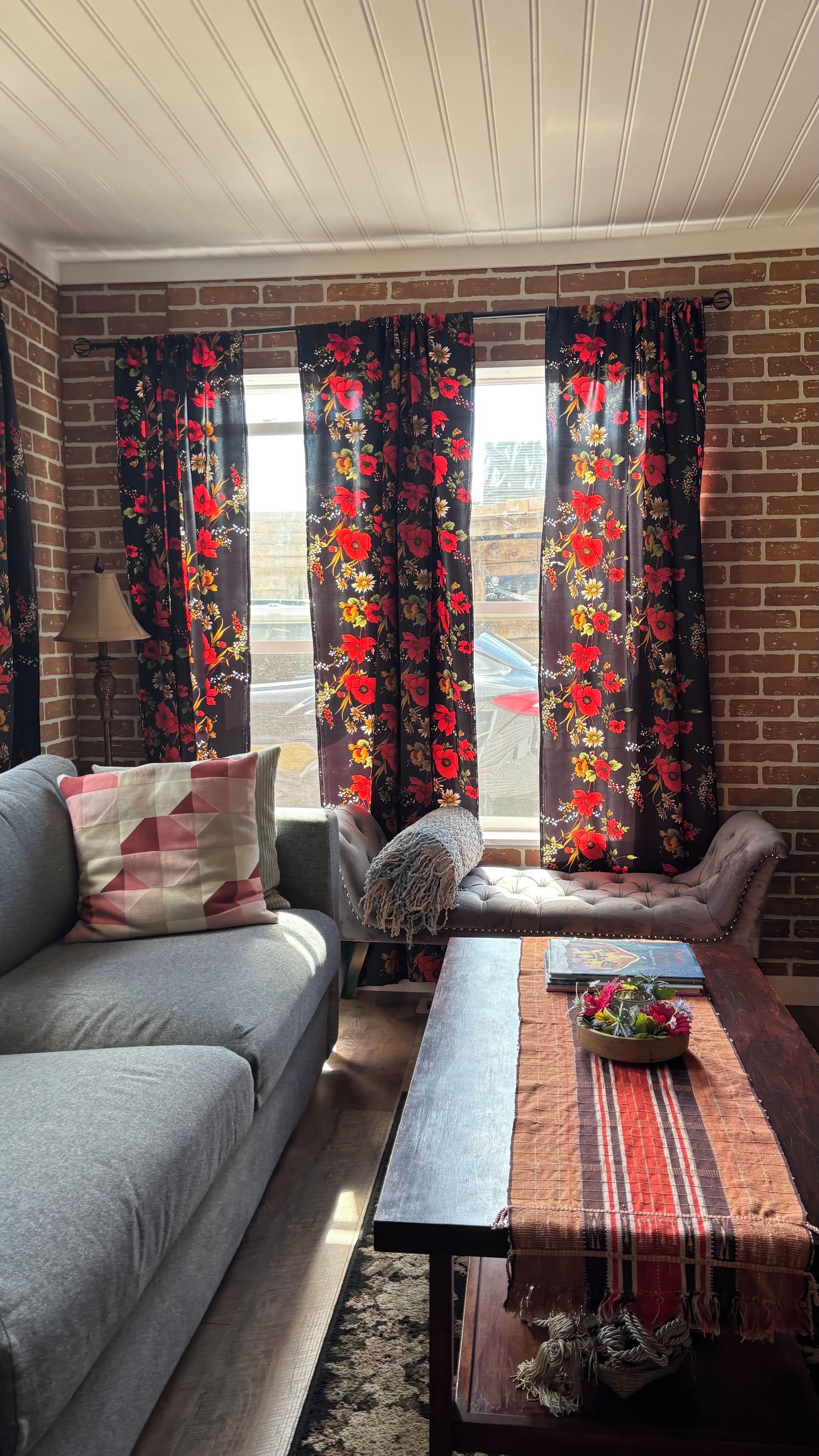 Un salon comprenant un canapé, une table basse et des rideaux à motifs floraux.