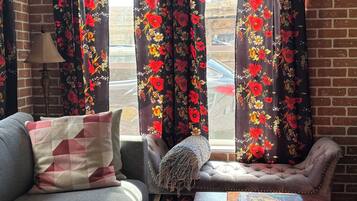 Un salon comprenant un canapé, une table basse et des rideaux à motifs floraux.