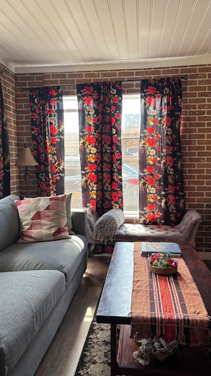 Un salón con sofá, una mesa de centro y cortinas estampadas con motivos florales.