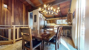 A wooden interior with a dining table, chairs, and a kitchen area. - Mountain Modern Townhome, Natural Light, Near The Village, On-Site Pool (Mammoth Lakes)