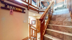 A wooden staircase with a metal handrail, a 'FAMILY' sign, and a 'MAMMOTTER ESTATE' parking permit on the wall. - Mountain Modern Townhome, Natural Light, Near The Village, On-Site Pool (Mammoth Lakes)