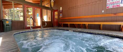 A hot tub with a wooden interior, a sign indicating no diving, and a capacity of 25 people.