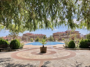 A swimming pool area with a stone pathway, benches, and a central planter.