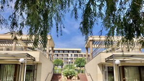 A modern building with a central staircase, surrounded by greenery and a clear sky. - Sorrento - Menada Apartments (Sveti Vlas)