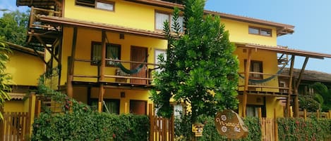 A yellow building with multiple balconies and a wooden fence.