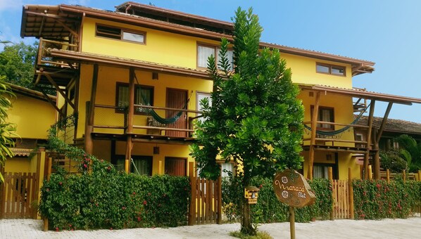 A yellow building with multiple balconies and a wooden fence.