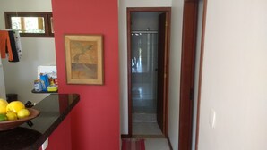 Eine Küche mit roter Wand, einem gerahmten Bild und einer Obstschale auf der Arbeitsplatte.