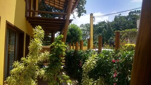 Ein Innenhof mit einer Holzpergola, Blumentöpfen und Blick ins grüne Umland.