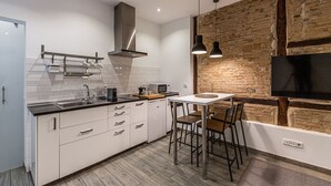 Een moderne keuken met witte kasten, een roestvrijstalen afzuigkap en een accentmuur van baksteen.