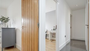 A hallway with a wooden door, a grey cabinet, and a desk with a chair. - Luxury Chic Apartment near Canary Wharf, Excel, O2 & Stratford (London)