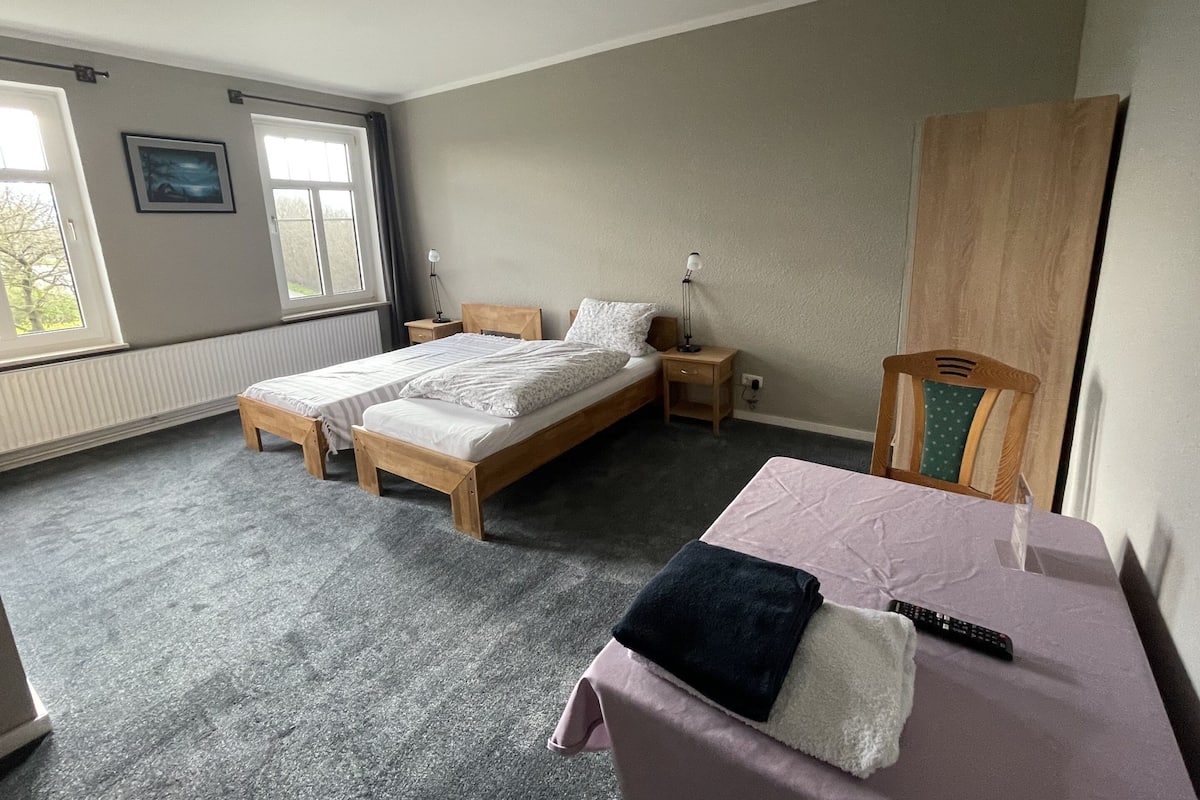 A bedroom with a double bed, bedside tables, a wardrobe, and a window.