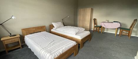Une chambre avec deux lits, une table de chevet, un bureau, une chaise et une armoire.