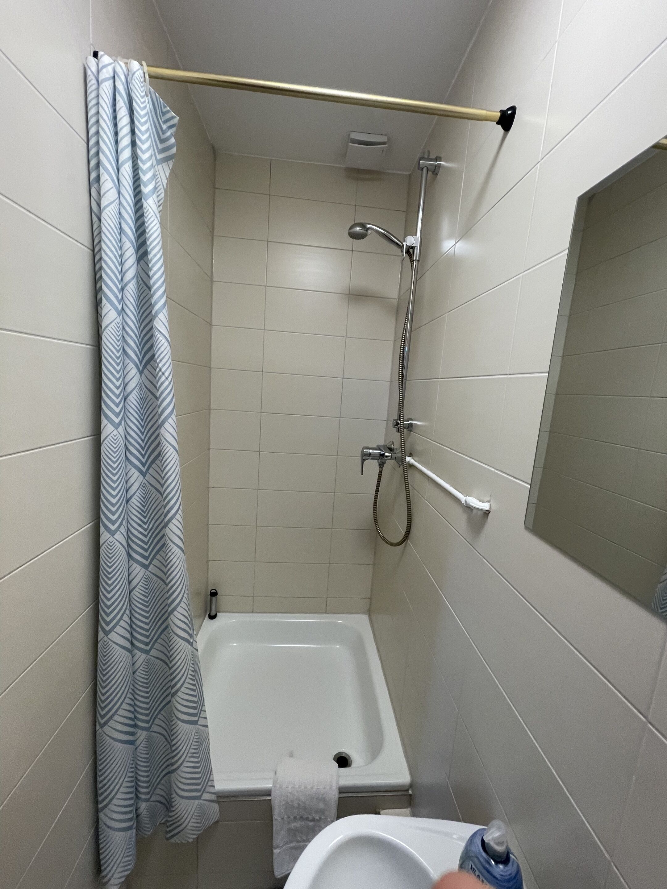 Un baño pequeño con ducha, inodoro y barra para toallas.