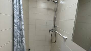 Un baño pequeño con ducha, inodoro y barra para toallas.