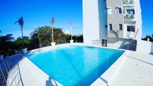 Piscina retangular com revestimento de azulejos brancos, rodeada por grades de metal.