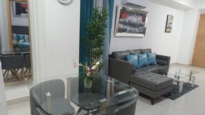 Uma sala de estar moderna com uma mesa de jantar de vidro, sofá cinza e um espelho grande.