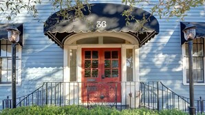 A house with a red door, a number 36 sign above the door, and a black awning with a scalloped edge. - The Retreat on Broad @ Trustees' Garden (Savannah)