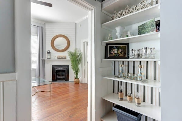 Una habitación con chimenea, un espejo y una estantería con objetos decorativos.