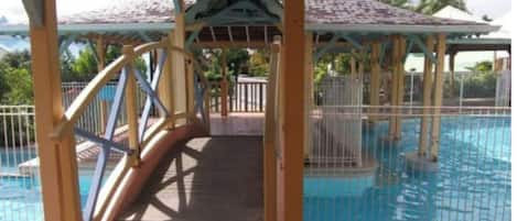 Uma área de piscina coberta com um deck de madeira e uma estrutura de gazebo.