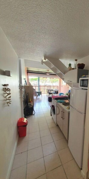 Enter a cozy space with a kitchen area featuring a refrigerator, microwave, and sink.