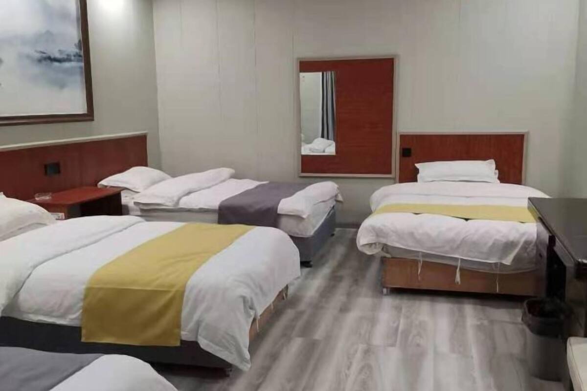 Ein Hotelzimmer mit zwei Betten, einem Holzkopfstück, einem Nachttisch, einem Spiegel und einem Bild an der Wand.