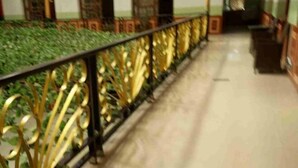 A corridor with a marble floor and a decorative railing with golden accents. - Gaji Hotel (Gyantse)