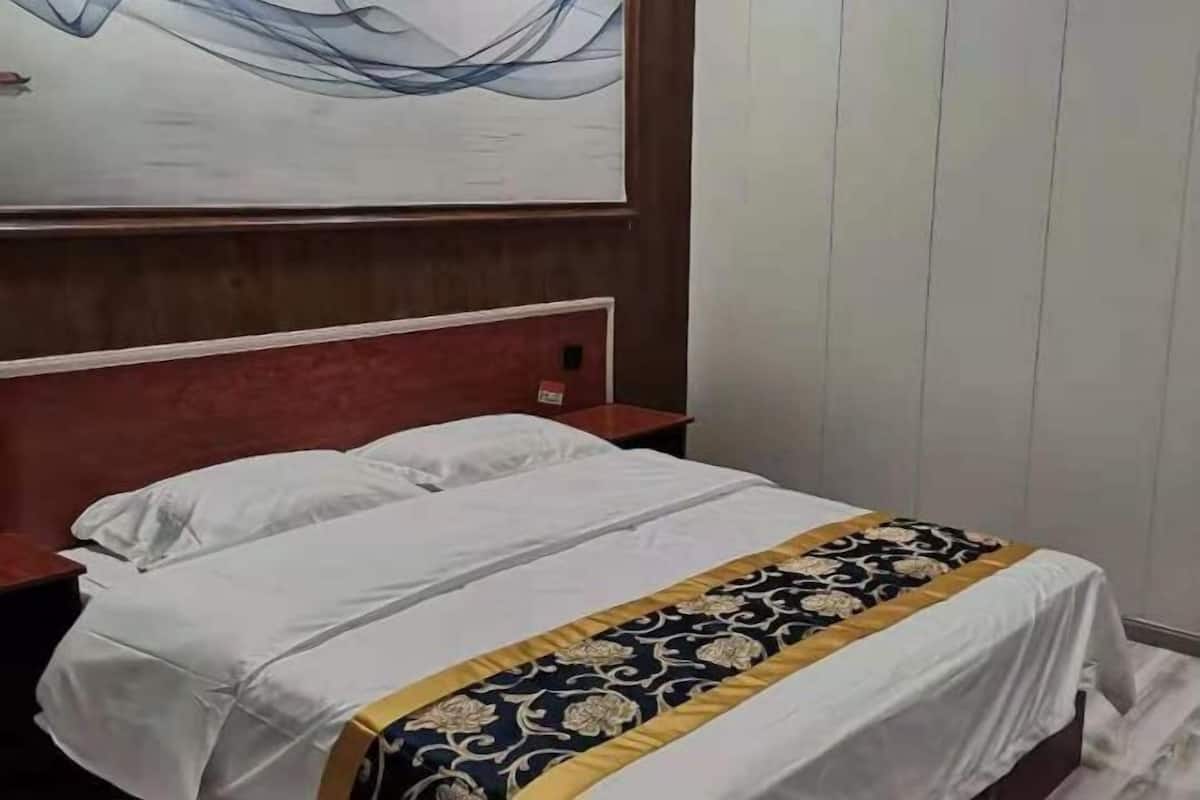 Ein Hotelzimmer mit Bett, Nachttisch und einem Bild an der Wand.